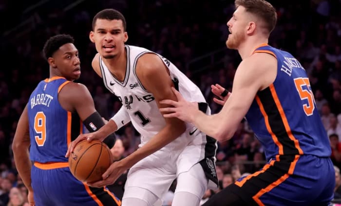 Wembanyama (in white) guarded by RJ Barrett (9) and Isaiah Hartenstein